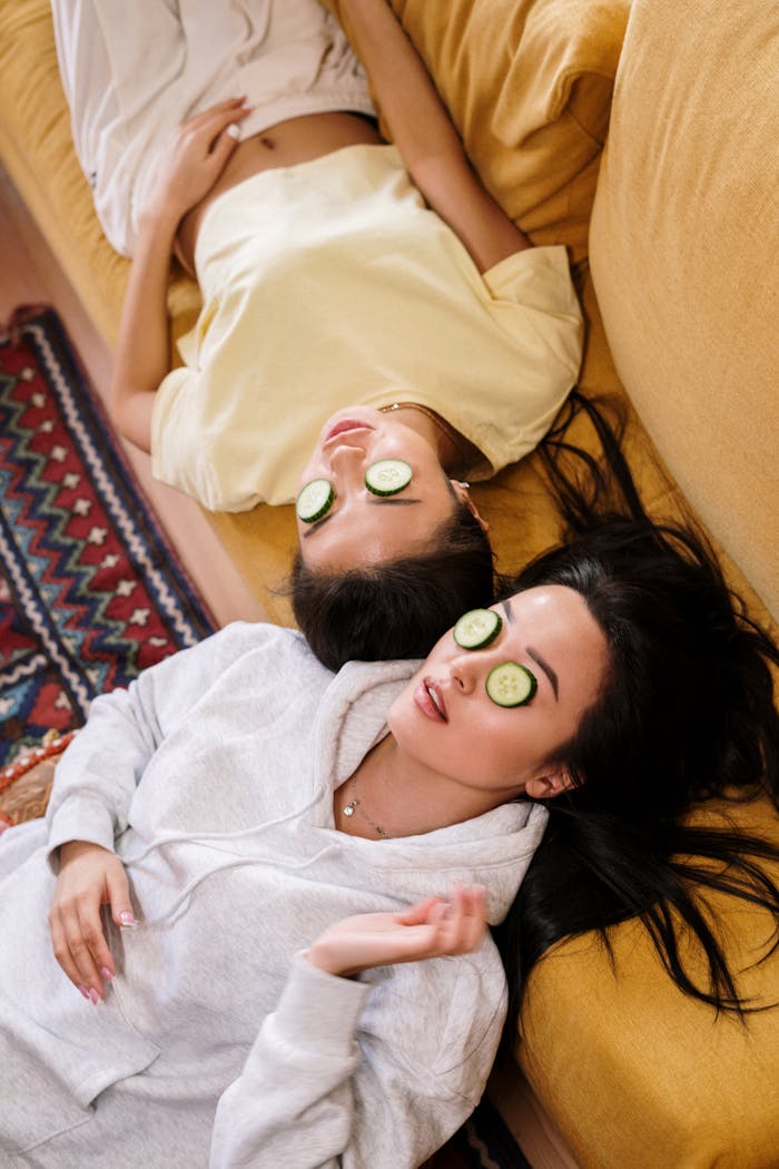 services-02 Two women enjoying a relaxing spa day with cucumber masks in a cozy home setting.
