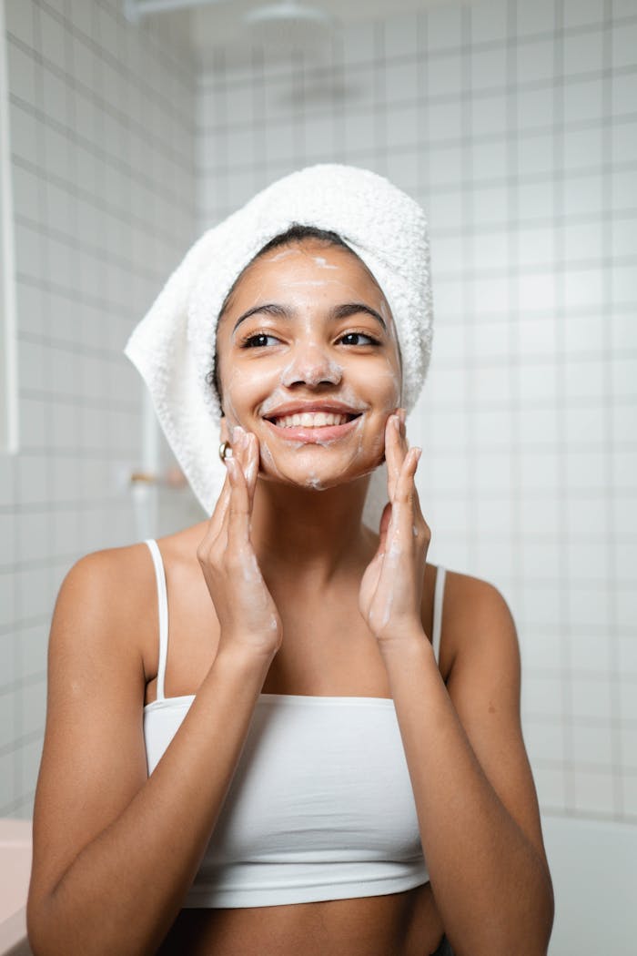 services-01 Smiling woman with face wash in a bathroom, embracing self-care and fresh skin.